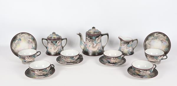 Japanese tea set in porcelain, Art Nouveau period, with polychrome decorations in relief of dragons: teapot, milk jug, sugar bowl and six cups with saucers (9 pcs.). The handle of one cup is glued back together and the edge of the teapot has two slight chips.