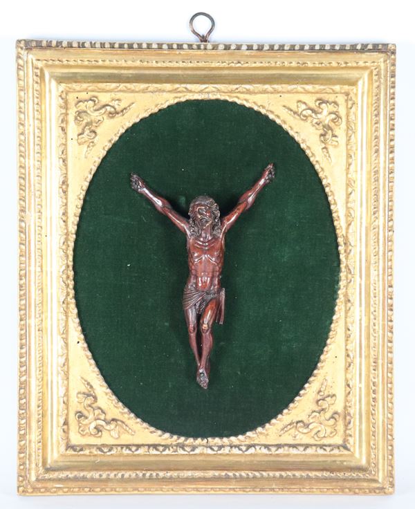 Antico piccolo Cristo in legno di bosso intagliato e patinato, montato su pannello in velluto verde in antica cornice ovale in legno dorato e intagliato