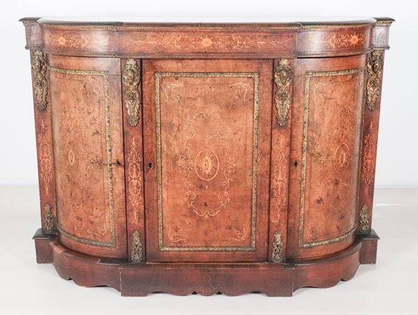 Antica servante francese Napoleone III, a forma semiovale bombata in noce, con intarsi in legno satinato a motivi neoclassici, fregi e guarnizioni in bronzo dorato, sbalzato e cesellato a motivi di mascheroni, tre sportelli