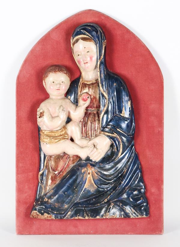 "Madonna col Bambino che regge una mela", antica scultura ad altorilievo in legno policromo, su supporto a sesto ovale in velluto rosa antico. Vari difetti