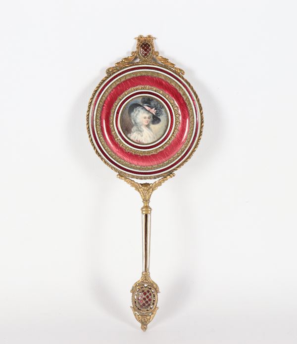 Antico specchio da toletta francese in metallo dorato e cesellato con guarnizioni in smalto rosso, al centro miniatura tonda dipinta "Ritratto di dama con cappello". Firmata