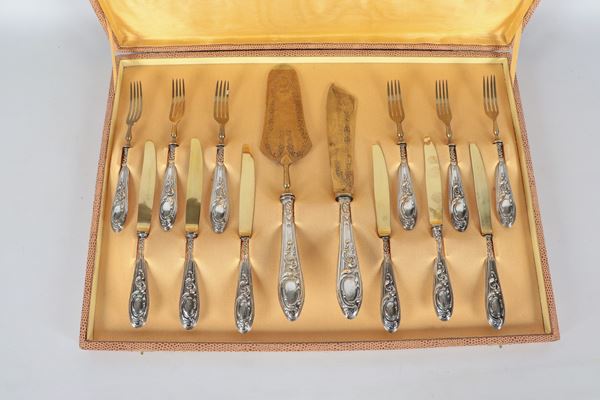 Antico servizio di posate da dolce con manici rivestiti in argento cesellato e sbalzato, lame e forchette in vermeil, annesso astuccio. (14 pz.)