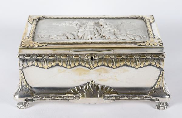 Antico scrigno in metallo argentato, sbalzato e cesellato, sul coperchio placca in biscuit bianco raff.nte "Scena galante", mancante della chiave