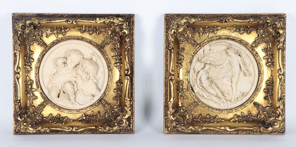Coppia di placche tonde in polvere di marmo raff.nti "Scena mitologica e due putti", cornici in legno dorato e riccamente intagliato