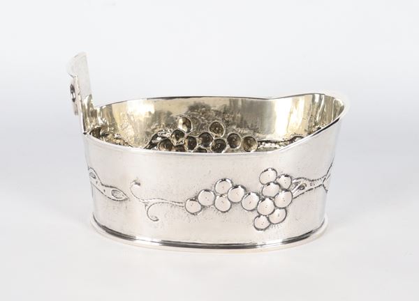 Piccolo versatoio ovale in argento cesellato e sbalzato a rilievo a motivi di grappoli d'uva, gr. 330