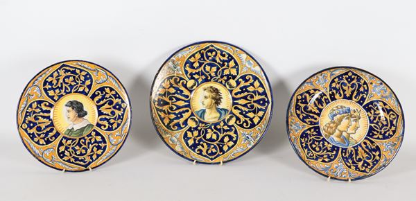 Lotto di tre antichi piatti da muro in maiolica lustrata di Faenza, interamente decorati a varie policromie con motivi di intrecci floreali e medaglioni centrali con ritratti di personaggi. Fine XIX Secolo