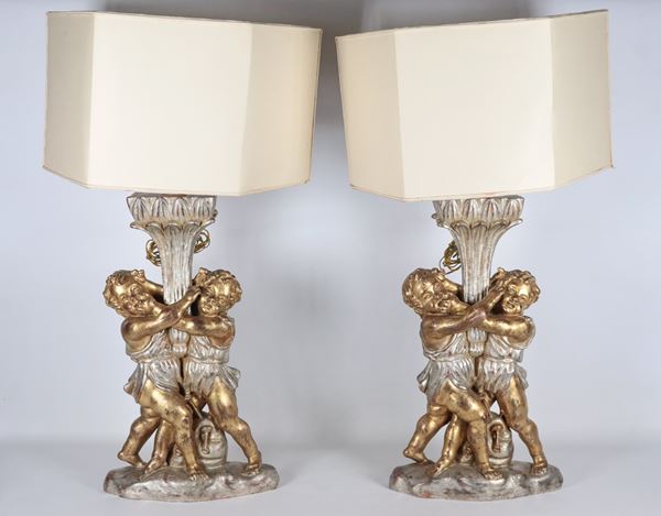 Coppia di lampade da tavolo in legno dorato e argentato con sculture di "Putti"