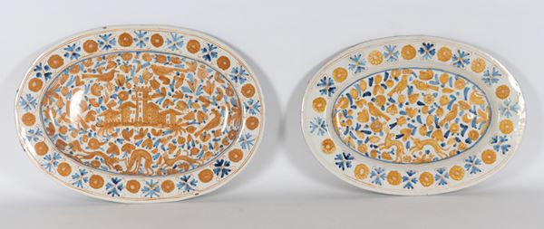 Lotto di due vassoi ovali in maiolica Deruta smaltata, decori policromi a motivi di case con torre e animali fantastici