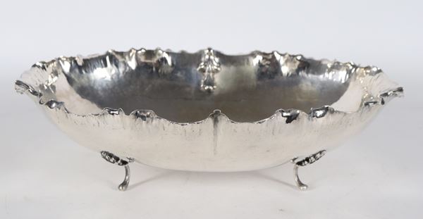 Fruttiera ovale in argento cesellato e sbalzato con bordo frastagliato, sorretta da quattro piedini ricurvi. Gr. 520