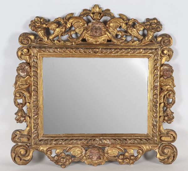 Piccola specchiera toscana Luigi XIV in legno dorato, intagliata a motivi di cherubini, aquile, cornucopie e volute di foglie d'acanto
