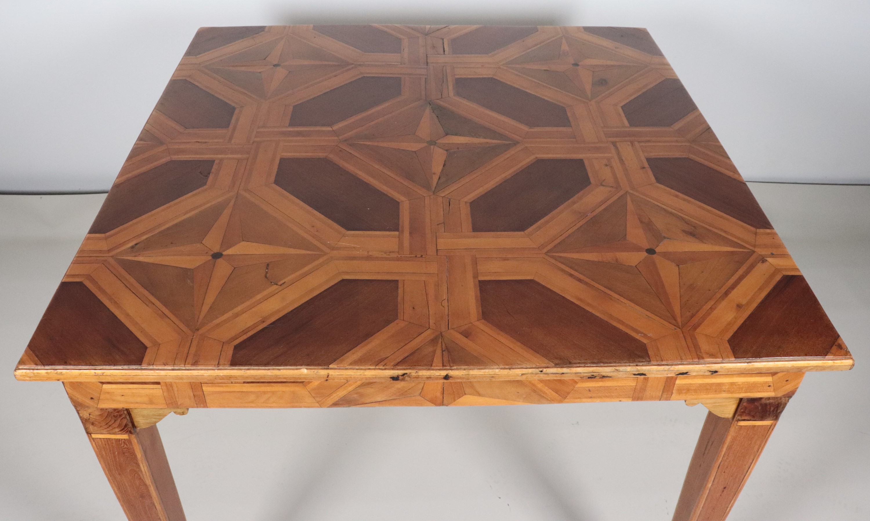 Tavolo quadrato da centro in noce, intarsiato a vari legni pregiati a motivi geometrici