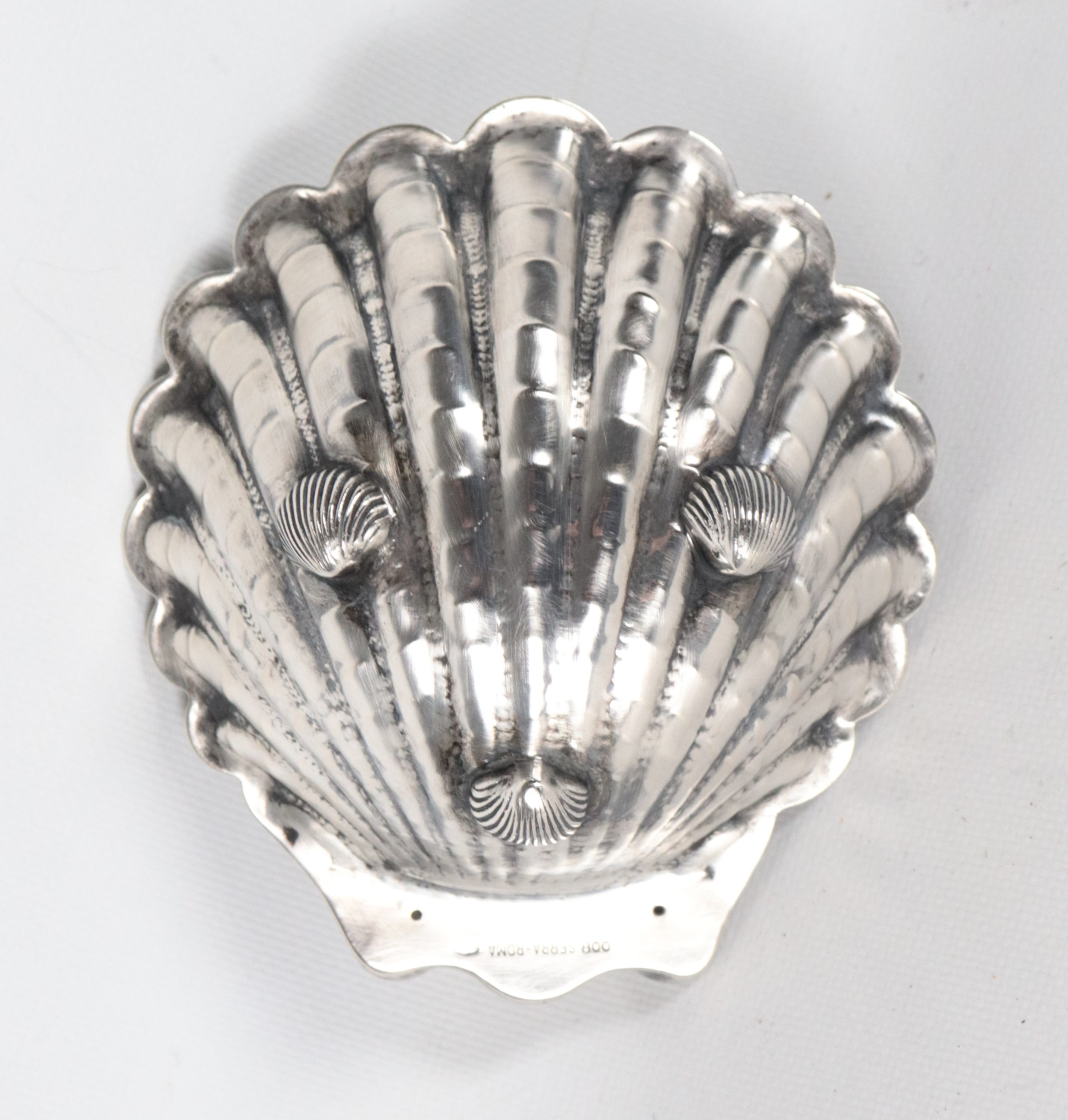 Conchiglia in argento cesellato e sbalzato, sorretta da tre piedini, gr. 185