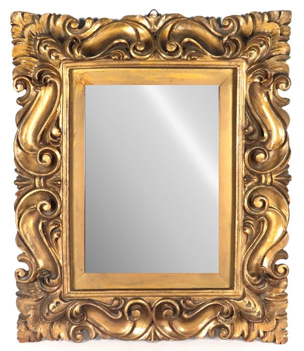 Richly carved gilded wood frame with Louis XIV motifs, mercury mirror inside