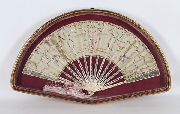 Antique fan decorated and colorful with allegorical scenes, musical instruments and tower with torches, in a gilded wooden showcase frame