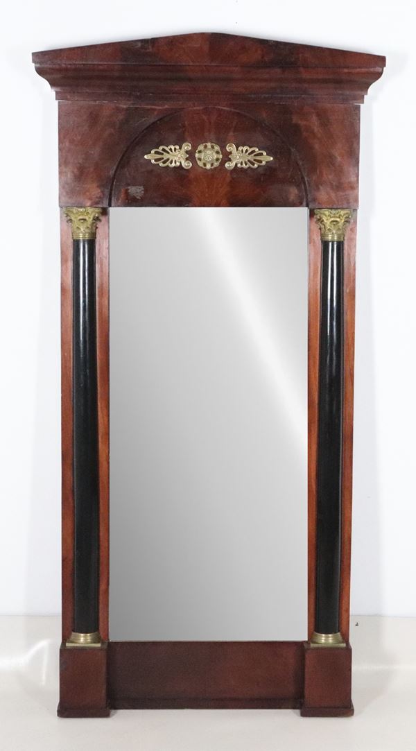 Antique Tuscan Empire mirror in mahogany and mahogany crotch, with black lacquered neoclassical column uprights. Gilded and chiseled bronze friezes and capitals, and a temple-shaped cornice.