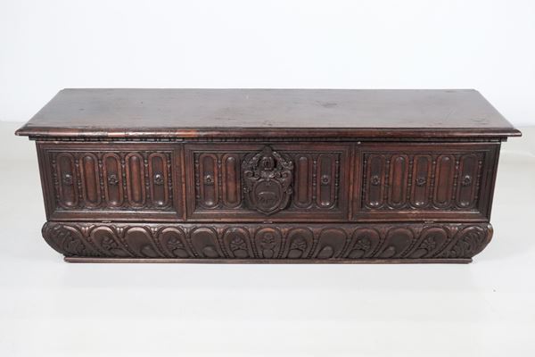 Antique chest in solid walnut, with front carved in relief with pilaster motifs and central family coat of arms