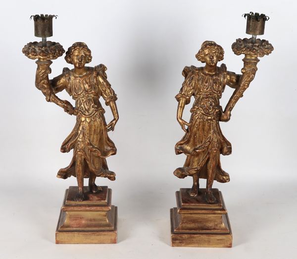 "Winged angels with cornucopias", a pair of sculptures in gilded and carved wood, supported by bases with a quadrangular column section.