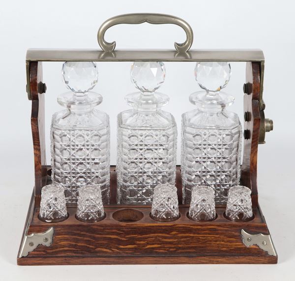 Antique English oak tantalus with three bottles and ten glasses in worked crystal 
