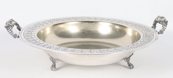 Large fruit bowl in silver metal with two handles and a chiseled palmette edge, supported by three curved feet