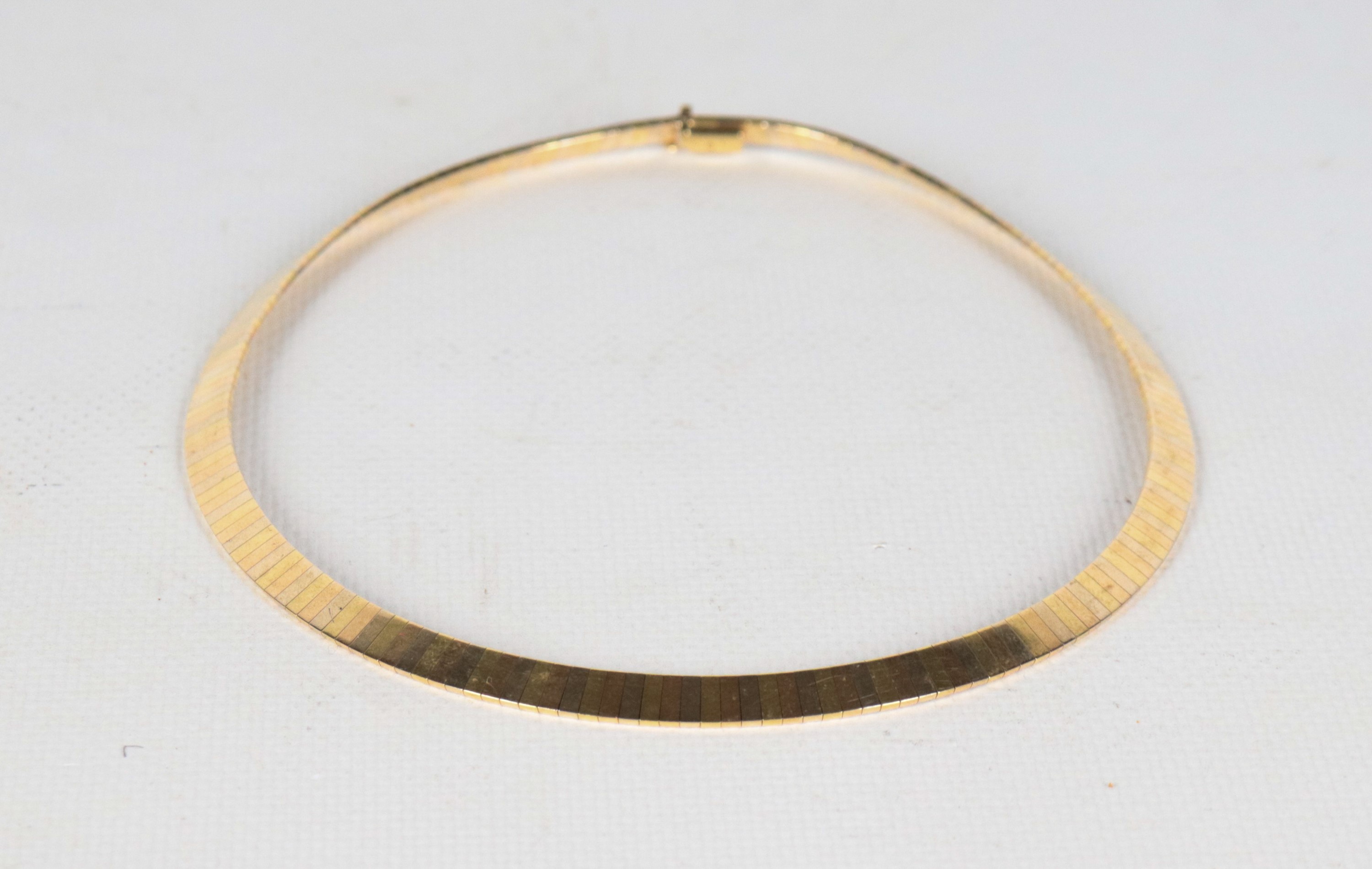 Collana girocollo a maglia rigida in oro 18kt a tre colori. Peso gr. 45