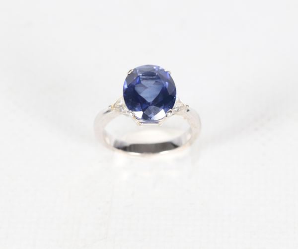 Anello in oro bianco 18kt, con quarzo blu ovale centrale e due piccoli diamanti laterali taglio fantasia ct 0,40 circa. Peso lordo gr. 5,5