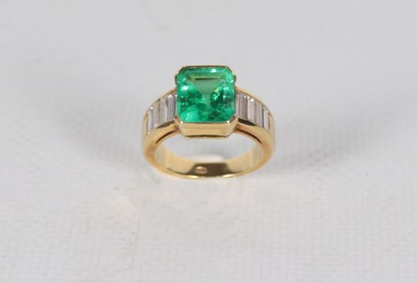Anello in oro giallo 18kt, con smeraldo centrale taglio carrè ct 4,5 circa e piccoli diamanti laterali taglio baguette. Peso lordo gr. 9 