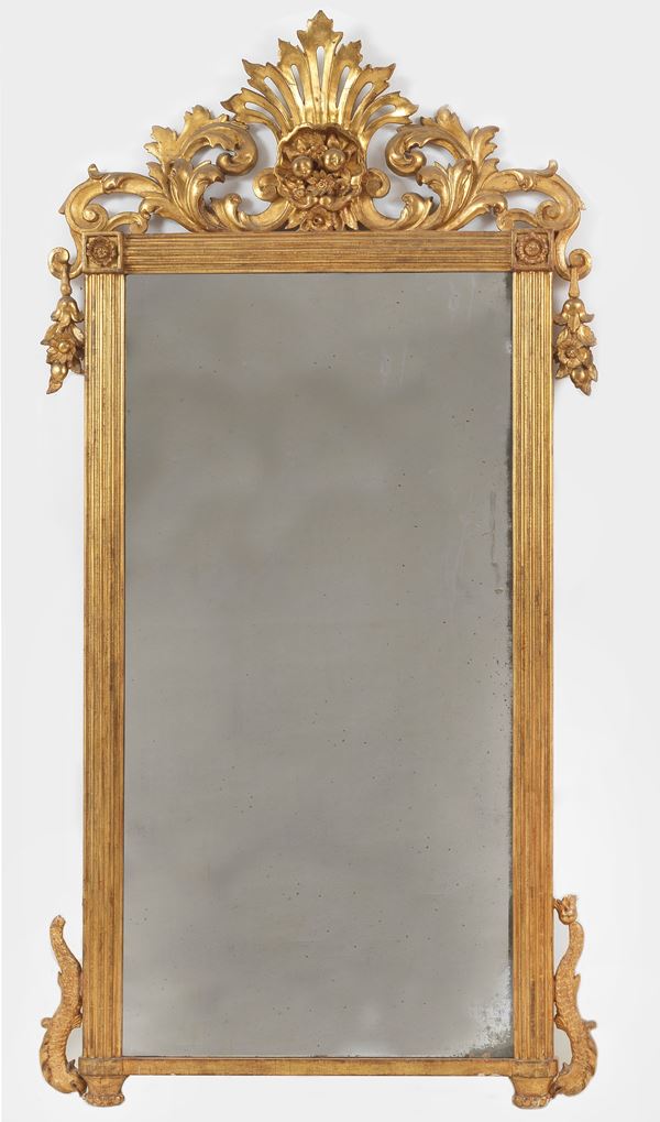 Antica specchiera Carlo X in legno dorato, con cimasa riccamente intagliata a volute di foglie d'acanto e calatine di fiori
