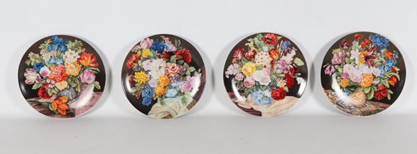 Lotto di quattro piatti da muro in porcellana, con decorazioni policrome riprese da nature morte di frutta e fiori