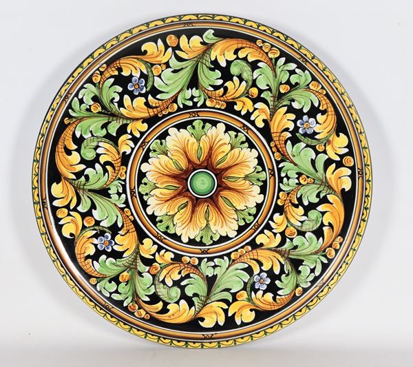 Grande piatto da muro in maiolica smaltata Caltagirone, con decorazioni policrome a volute floreali e rosone centrale 
