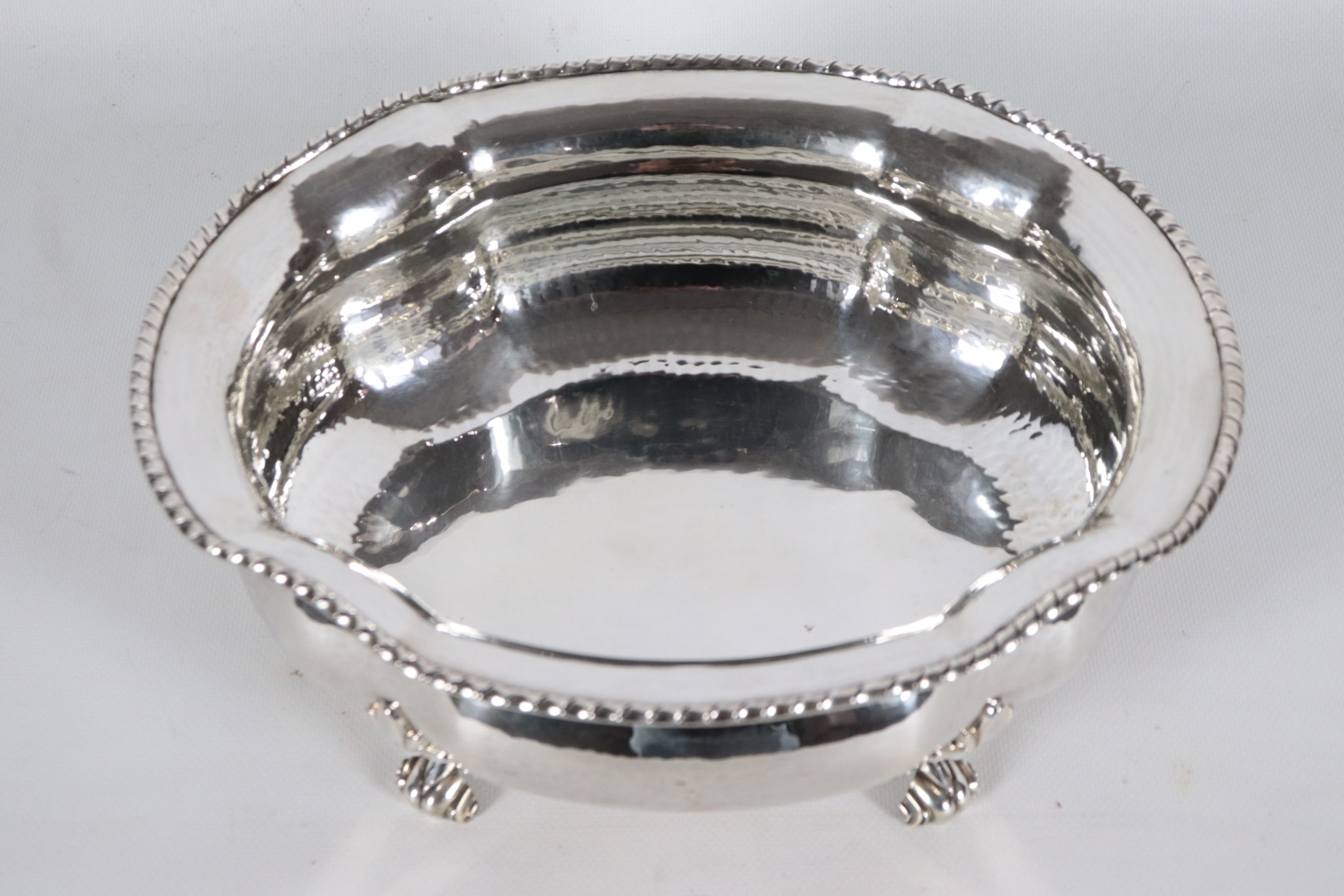 Fruttiera ovale in argento con bordo centinato, cesellato e sbalzato, sorretta da quattro piedini...