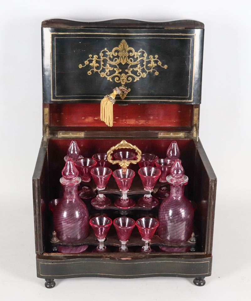 Antico scrigno in legno ebanizzato con intarsi in legno dorato, all'interno servizio da liquore c...