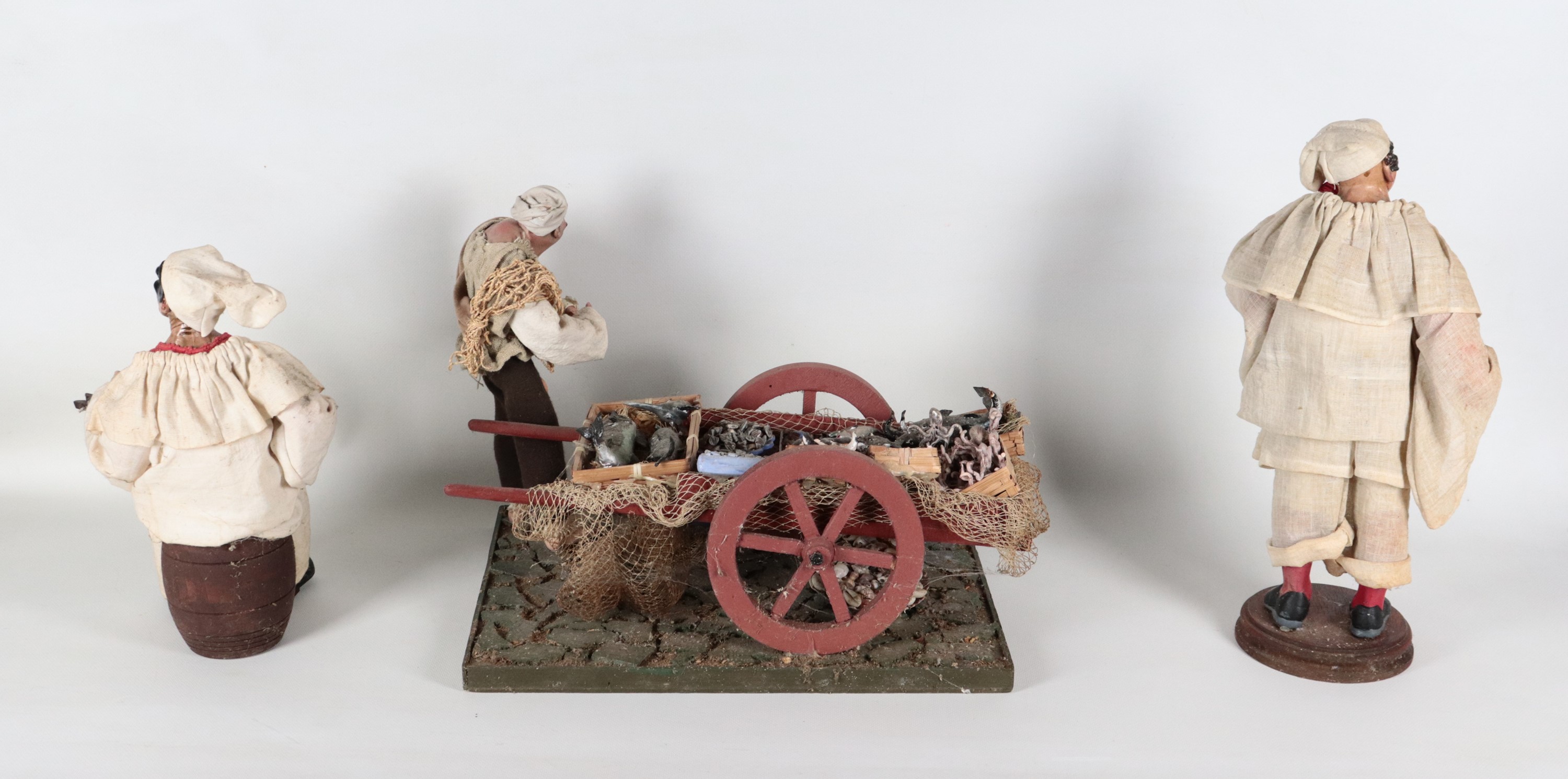 "Due pulcinella suonatori e venditore di pesce con carretto", lotto di tre pupazzi del presepe na...