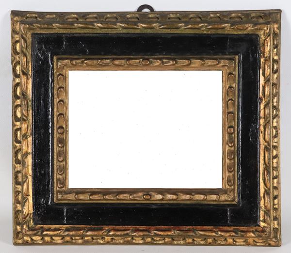 Antica piccola cornice in legno ebanizzato, dorato e intagliato