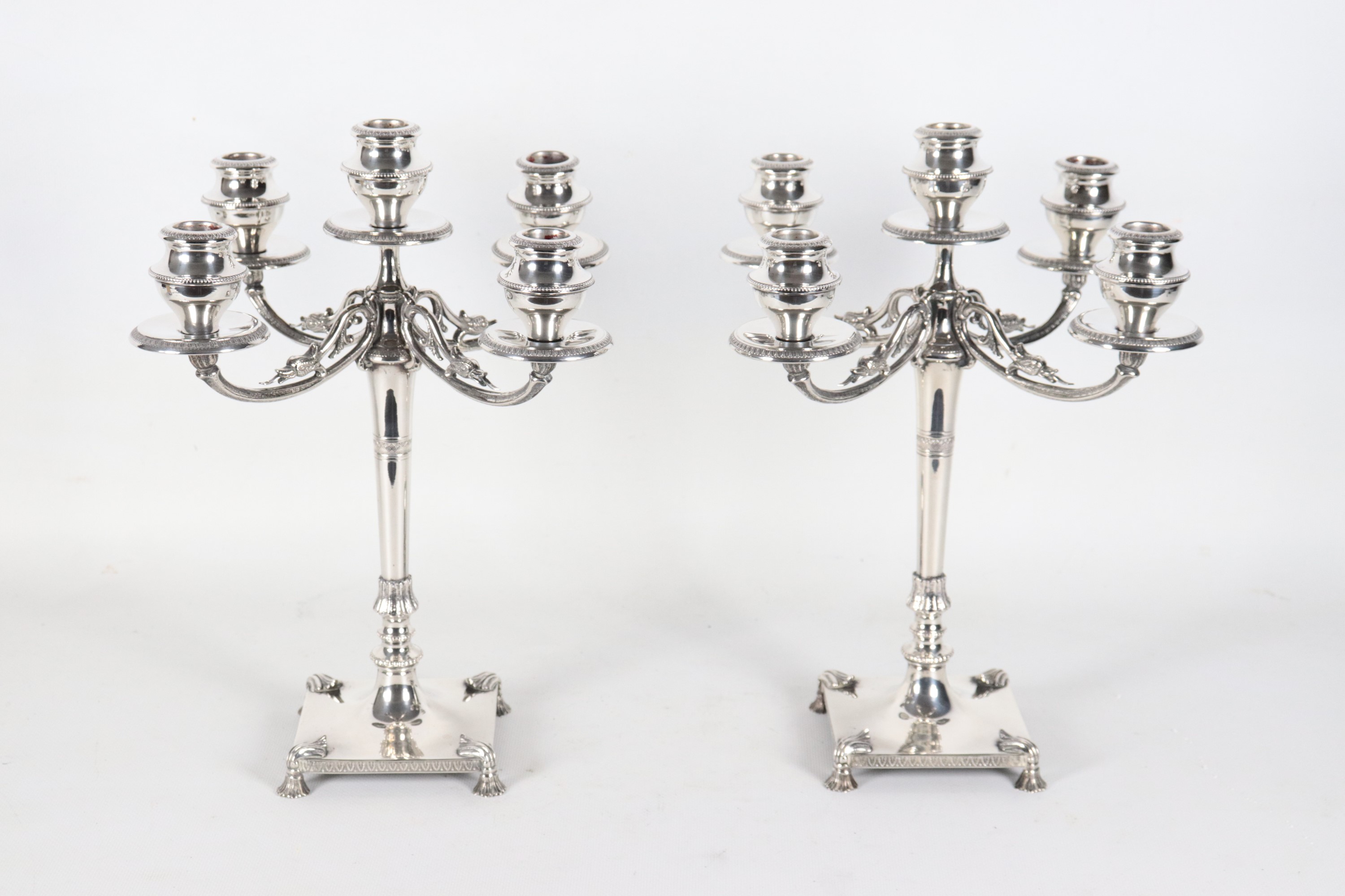 Coppia di candelabri in argento cesellato e sbalzato a motivi Impero, cinque fiamme ciascuno, gr....