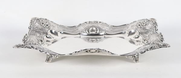 Centrotavola in argento titolo 925 a forma rettangolare centinata, con bordo cesellato e sbalzato a volute floreali, gr. 805