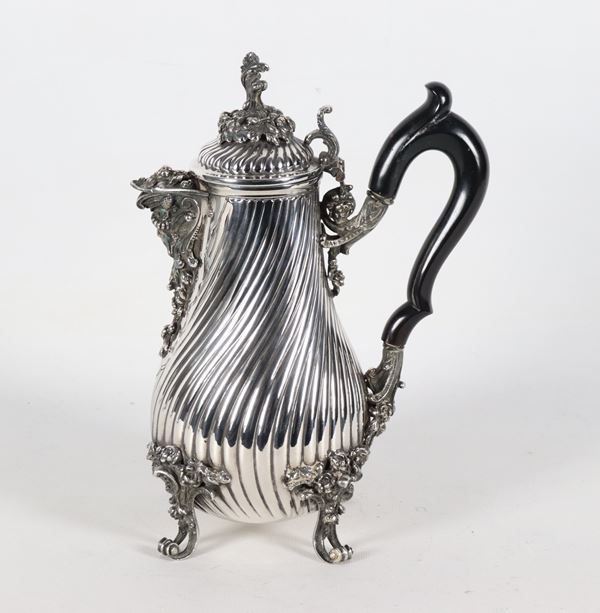 Caffettiera in argento cesellato e sbalzato a torchon, con becco a forma di mascherone e piedini ricurvi, manico in legno ebanizzato, gr. 1230