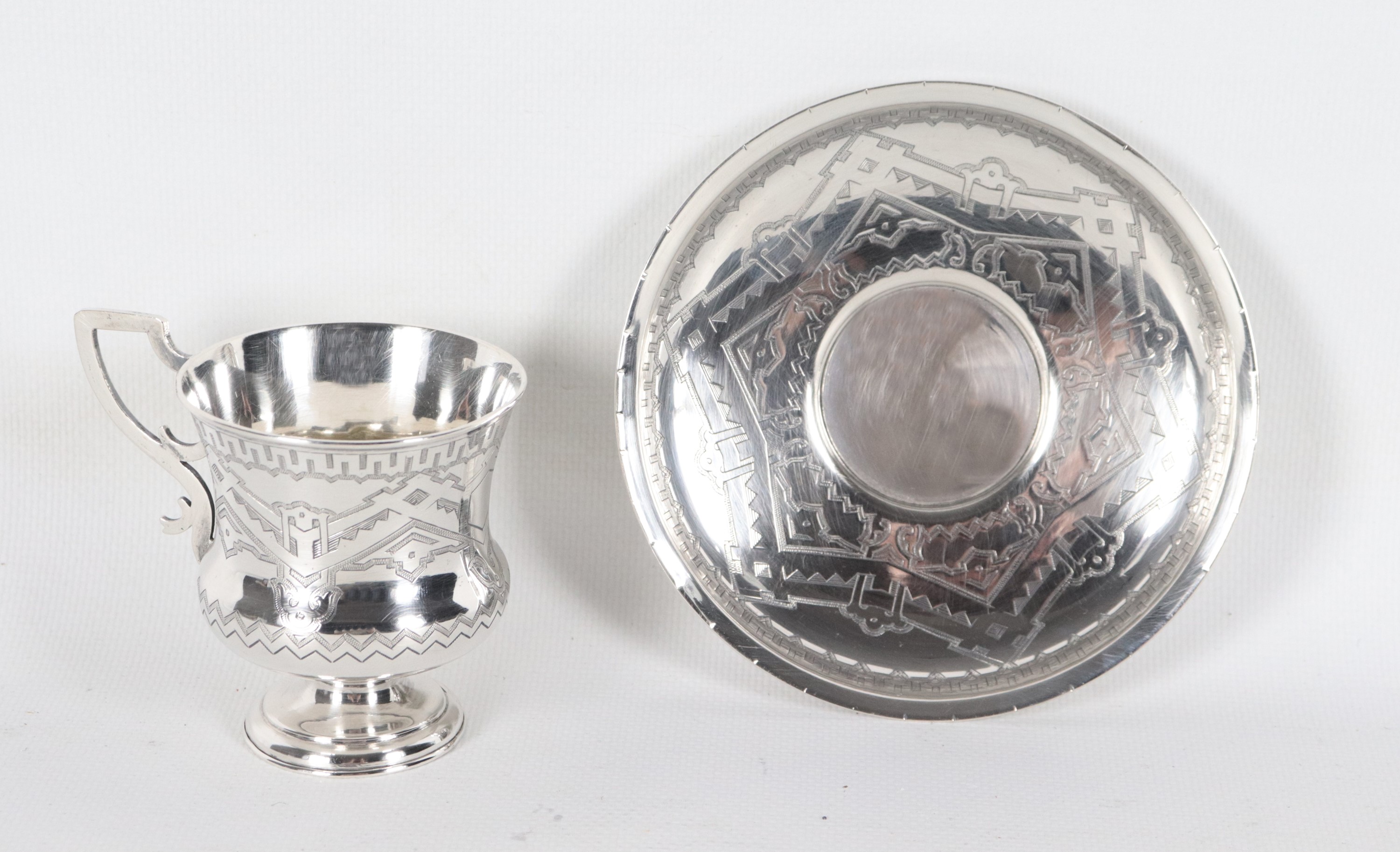 Antica tazzina con piattino, in argento cesellato e sbalzato a motivi di intrecci geometrici, gr....