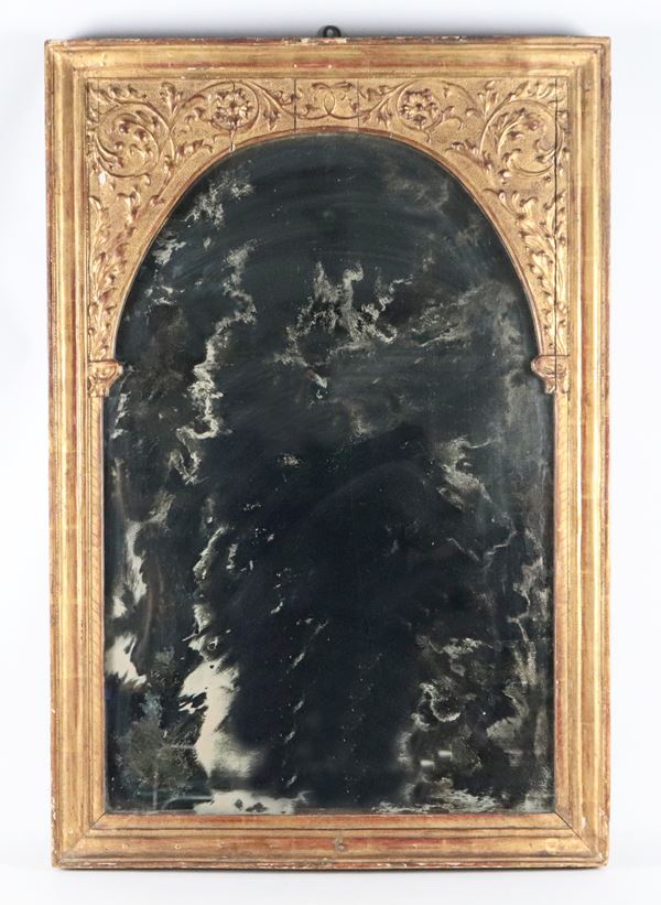 Antica cornice a sesto ovale, in legno dorato e intagliato a motivi di volute floreali