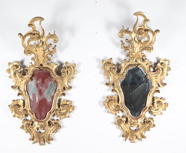 Coppia di antiche specchiere in legno dorato e riccamente intagliato a motivi Luigi XV di volute di foglie d'acanto, ricci e fiori, specchi al mercurio