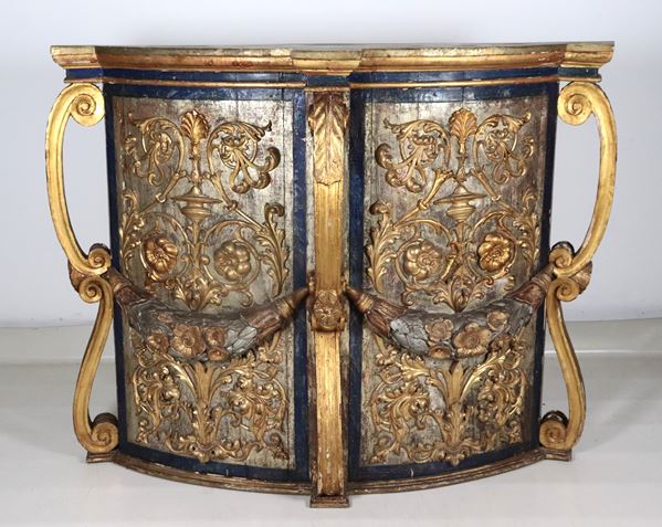 Mobile da muro a forma sagomata bombata in legno laccato e dorato, riccamente intagliato a motivi Luigi XVI su fondo argentato a mecca