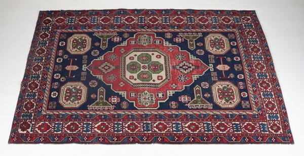 Persian Kazak rug with geometric design and central diamond in red on a blue background