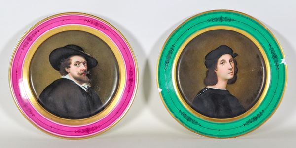 A pair of porcelain wall plates with painted medallions depicting "Raffaello Sanzio" and "Paul Rubens." One plate has cracks.