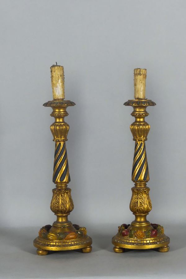 Coppia di candelieri in legno dorato e decorato.