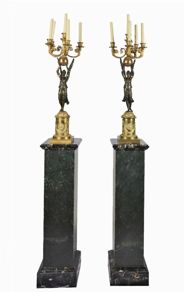 Pair of large candelabra with sculptures of "Winged Victories" in patinated and gilded bronze