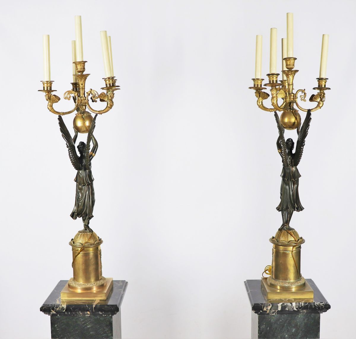 Coppia di grandi candelabri con sculture di "Vittorie alate" in bronzo patinato e dorato