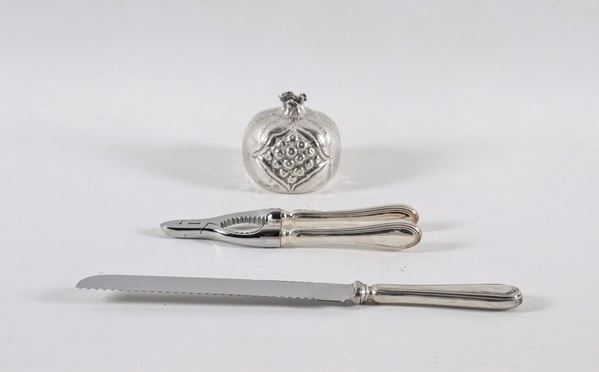 Lotto in argento cesellato e sbalzato di un accendino da tavolo a forma di melagrana, uno schiaccianoci e un coltello da pane (3 pz)