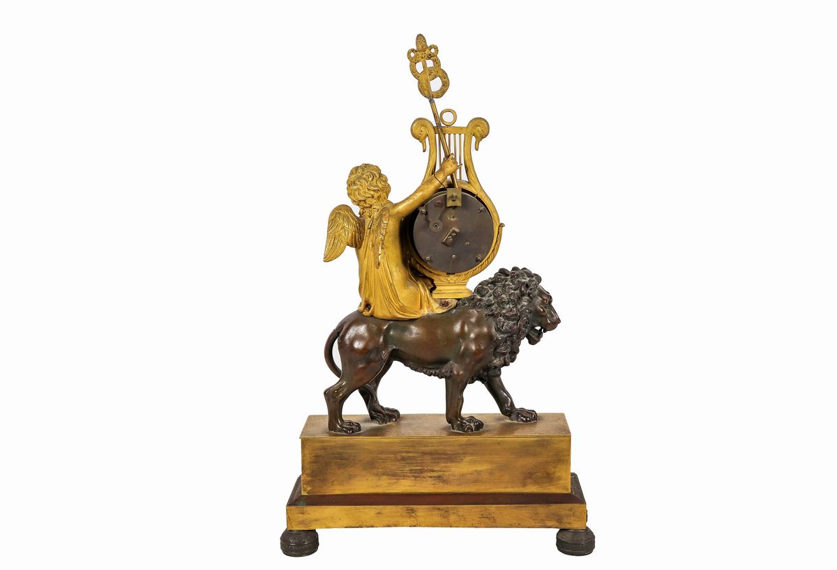 Pendola da tavolo Impero in bronzo dorato e patinato con sculture di "Putto e leone" e quadrante ...