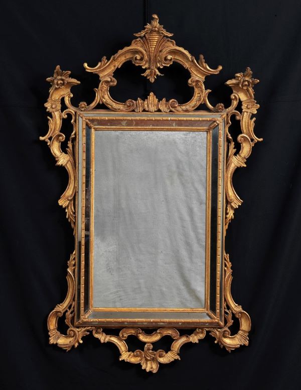 Specchiera in legno dorato ed intagliato a motivi Lugi XV a volute di foglie d'acanto, fiori e ricci