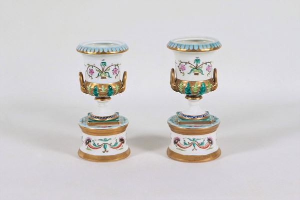 Coppia di piccoli vasi a forma di anfore in porcellana tedesca con decorazioni variopinte a motivi neoclassici e lumeggiature in oro zecchino