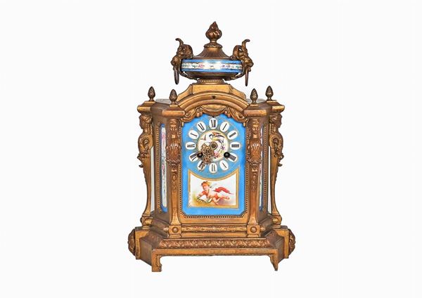 Antica pendola da tavolo francese in bronzo dorato, sbalzato e cesellato con placche in porcellana policroma di Sevres decorate a motivi di putti e ghirlande floreali